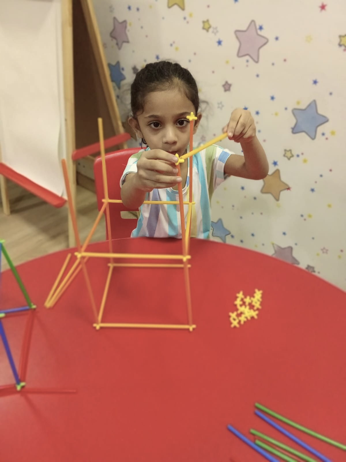 A child building a tall structure from connecting sticks