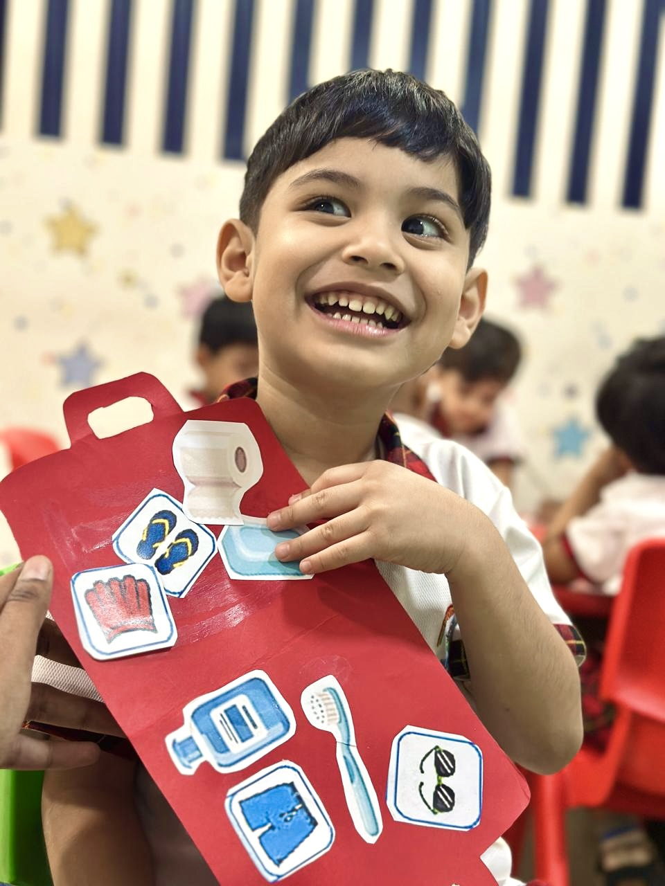 A smiling child holding up a craft they have made