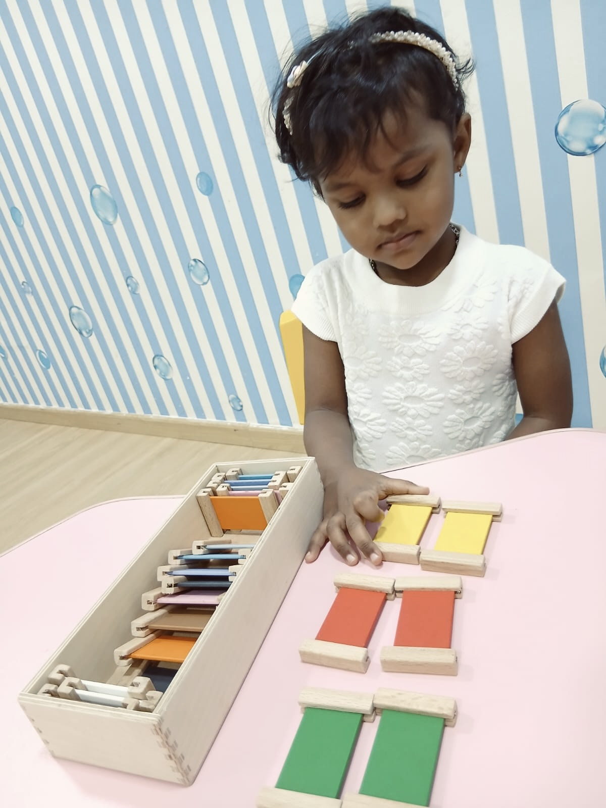 A child matching colour tablets on a wooden tray