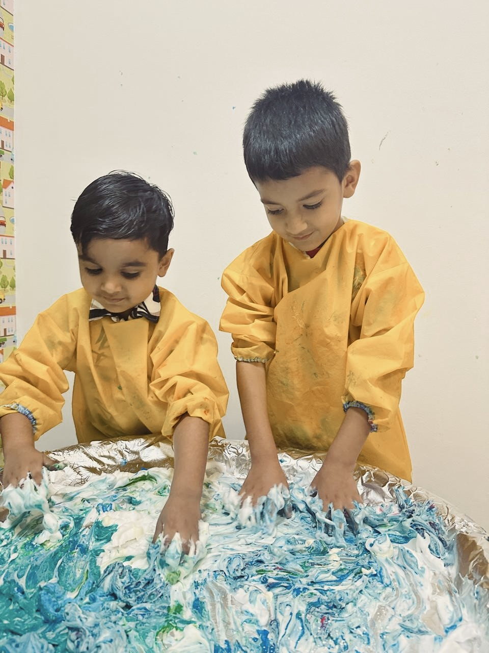 Two children exploring textured paint with their hands