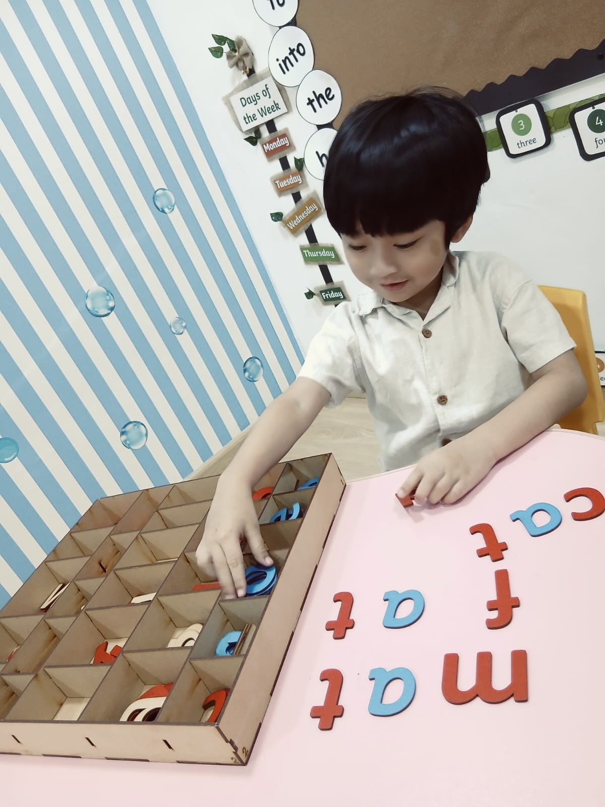 A child spelling words with a wooden moveable alphabet