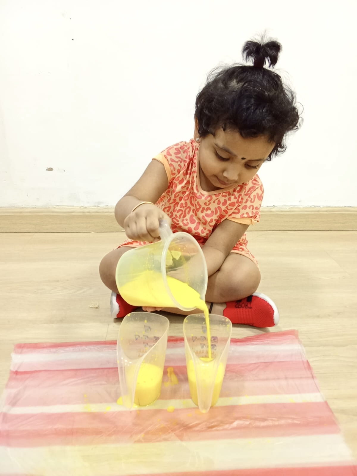 A child carefully pouring juice into cups during a practical-life activity